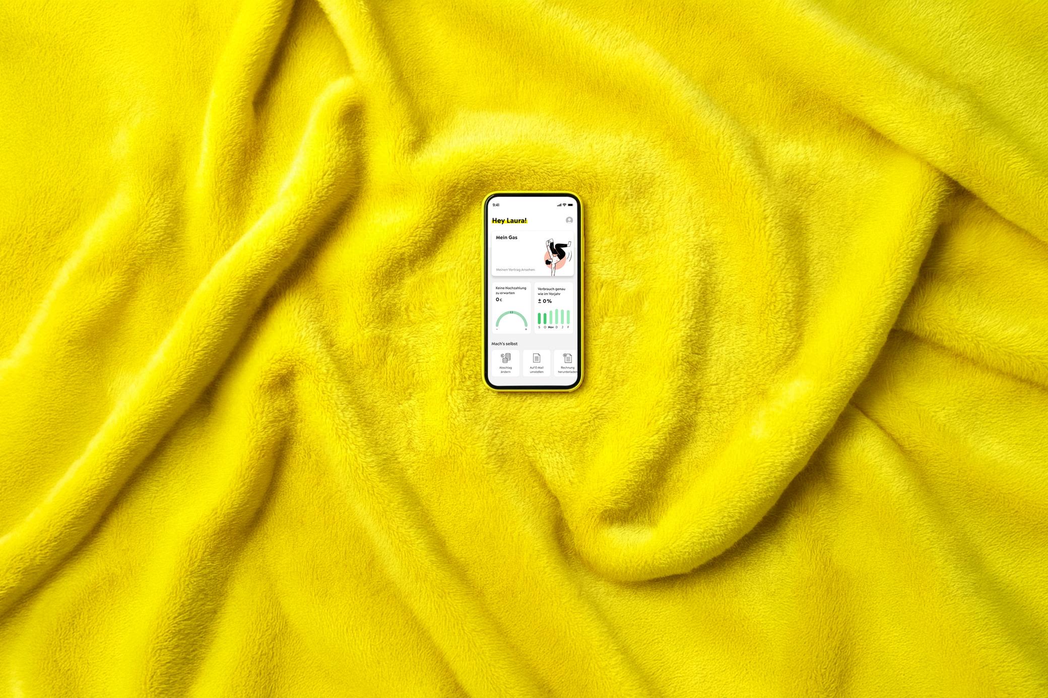 Unsere Yello Gas- und Heiztarife für dein warmes Zuhause Ein Smartphone auf warmer, gelber Decke zeigt Bildschirm für Gastarif in der Yello App - KI generiert