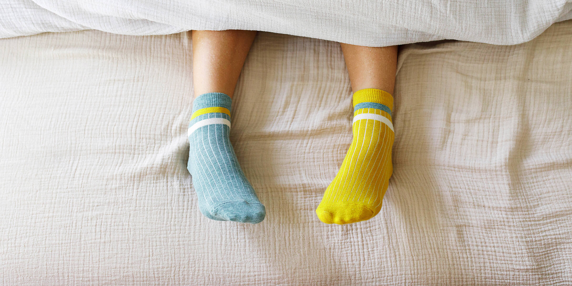Reduzierte Umlagen für deine Wärmepumpe? So geht’s. Füße in warmen Stricksocken liegen auf einer Bettdecke